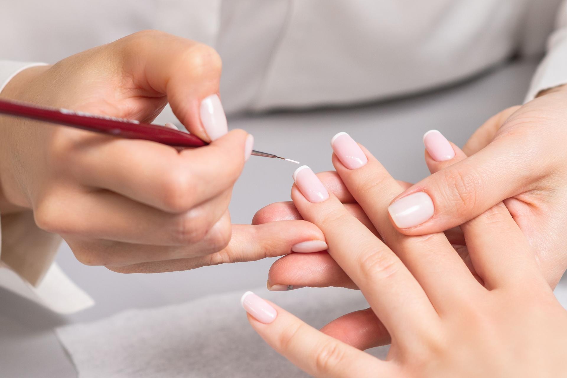 Woman receiving french manicure by beautician